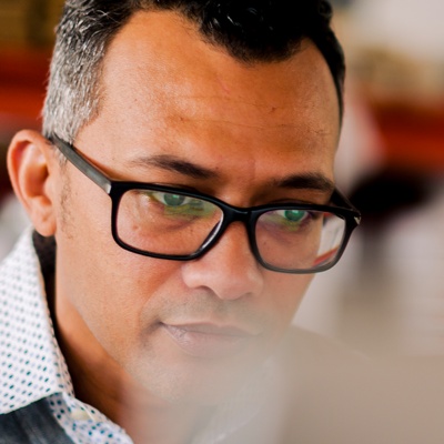 A man wearing glasses looking down toward a computer screen.